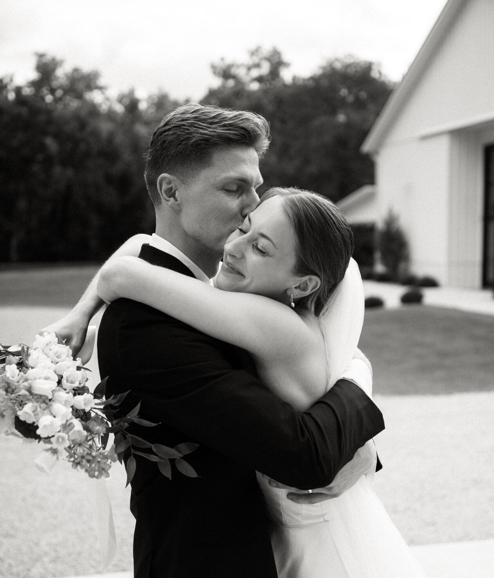 a couple joyfully embraces in front of a white building after getting married